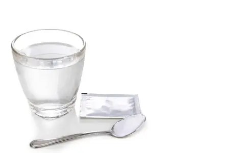 Szklanka wody, saszetka i łyżeczka z proszkiem – zestaw do walki z odwodnieniem po alkoholu.