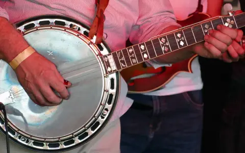 Ein Mann spielt ein Banjo, ein Saiteninstrument mit einem runden Korpus und einem langen Hals.