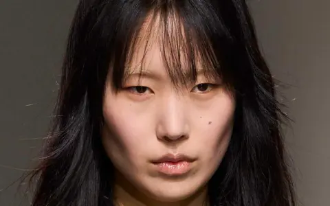 Rostro de modelo con cabello negro y flequillo desordenado, un corte **hush cut** que enmarca su rostro.