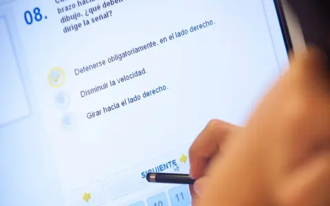 Persona haciendo un test de conducir en una tablet. La pregunta 8 es sobre una señal. ¿Cuántos test hay que hacer para aprobar el teórico?