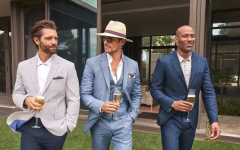 Stylish men in suits and blazers, perfect for ideas on what to wear to a wedding men. They hold champagne glasses.