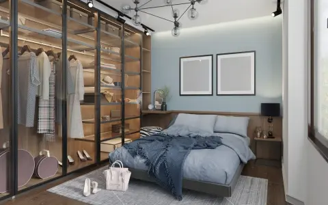Chambre moderne avec dressing vitré bien organisé, lit bleu douillet et deux cadres vides au mur.