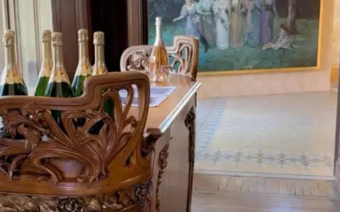 Bouteilles de champagne sur un meuble sculpté dans la maison Demoiselle à Reims. Un tableau orne le mur.