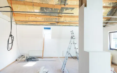 Chantier en cours : câbles électriques apparents, échelle, et matériaux. Projet de refaire électricité sans saignées en vue.