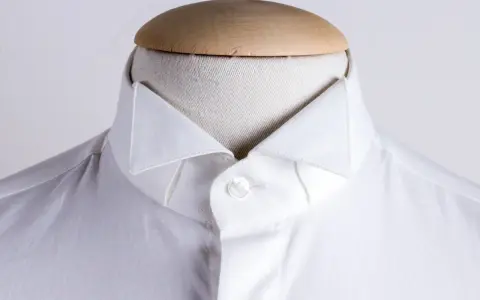 Dettaglio di una camicia bianca su un manichino, che mostra i diversi tipi di colletto camicia.