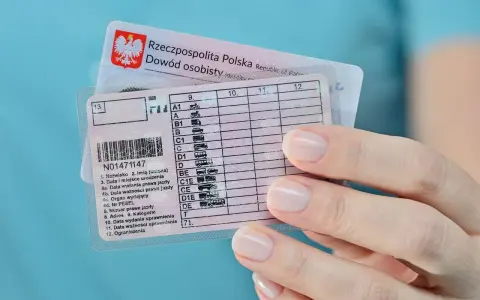 Dłoń trzyma polskie prawo jazdy z zaznaczoną kategorią B. Widoczny też dowód osobisty.