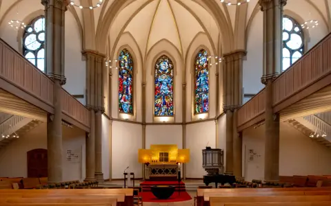 Festlicher evangelischer Gottesdienst am Heiligabend in einer Kirche mit Buntglasfenstern und Holzbänken.