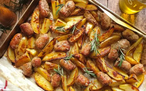 Salsiccia e patate al forno, dorate e profumate al rosmarino, pronte per essere gustate.