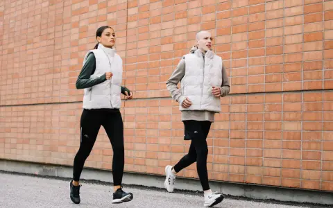 Coppia corre lungo un muro di mattoni. Ottimi consigli per correre in coppia, con abbigliamento tecnico.