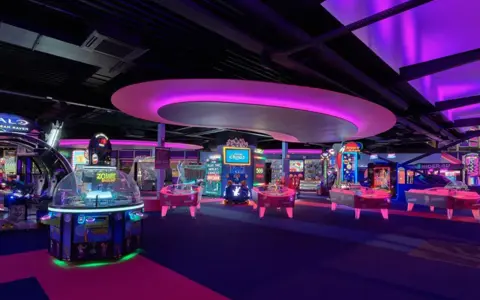 Bunte Spielautomaten und Air-Hockey-Tische in einem beleuchteten Gamestate Potsdamer Platz.