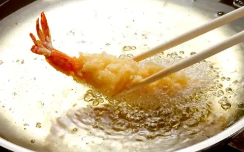 Krewetka w chrupiącej panierce panko smaży się w gorącym oleju.
