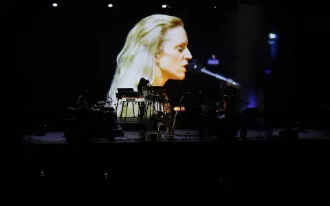 Agnes Obel na ekranie i zespół na scenie podczas koncertu.