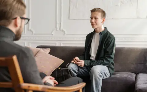 En ung man sitter i samtal med en terapeut. En viktig del av psykoterapi behandling är att skapa en trygg miljö.