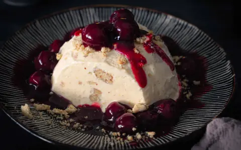 Cremiges Eisparfait mit Kirschsauce und Streuseln, ein köstliches Rezept für heiße Tage.