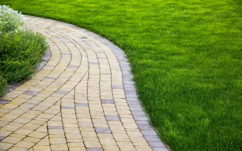 Vialetti giardino fai da te in pietra, con prato verde curato e aiuole fiorite.