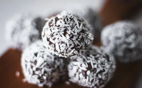 Nära bild på protein chokladbollar täckta med kokosflingor. Perfekt för ett snabbt mellanmål.