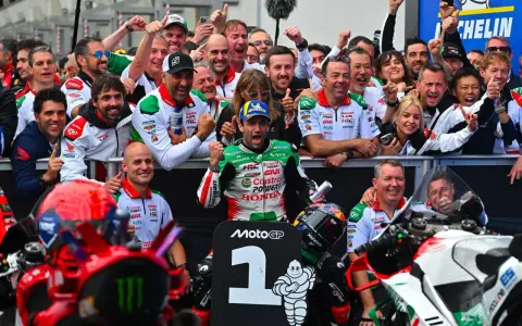 El equipo celebra un podio en el calendario MotoGP. El piloto número 1, rodeado de su equipo, muestra su alegría.