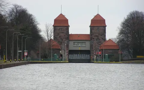Die Schachtschleuse Minden mit ihren markanten Türmen und roten Ziegeldächern ragt über das ruhige Wasser.