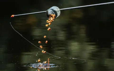 Karmnik method feeder wysypuje zanętę do wody, tworząc chmurę przynęty dla ryb.