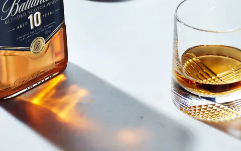 Butelka Ballantine's 10 Years Old i szklanka z bursztynowym płynem, przypominającym smak bourbona.
