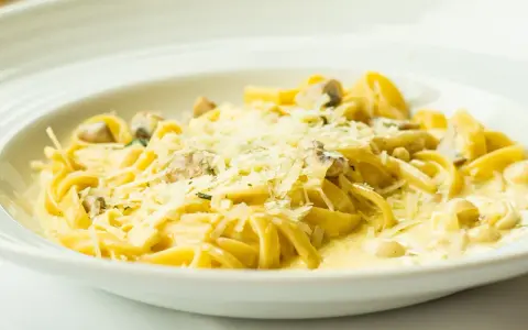 Pyszny makaron z grzybami w kremowym sosie, posypany parmezanem. Idealny przepis na obiad.