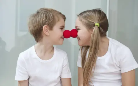Uśmiechnięte rodzeństwo z czerwonymi nosami klauna na nosach.