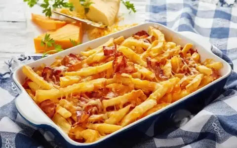 Zapiekane frytki z serem i chrupiącym boczkiem, podane w niebieskiej brytfance na kratkowanym obrusie.