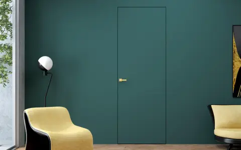 Nowoczesne drzwi wewnętrzne z ukrytymi zawiasami, idealnie wtapiające się w ścianę. Złota klamka dodaje elegancji.