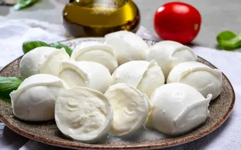 Frische Mozzarellakugeln auf einem Teller, garniert mit Basilikum. Perfekt für eine leichte Mahlzeit während der Schwangerschaft.
