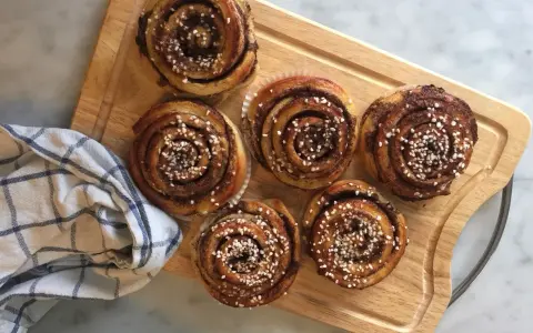 Sju gyllene kanelbullar med pärlsocker, redo att avnjutas. En härlig påminnelse om hur bakar man.