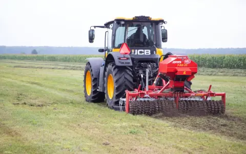 Ciągnik JCB z rozsiewaczem nawozu na polu.