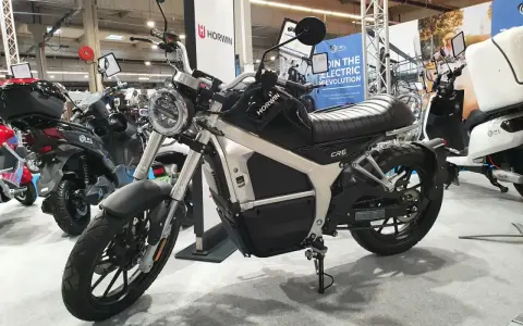 Czarny motocykl elektryczny Horwin CR6 na wystawie, obok innych skuterów.