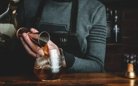 Barman nalewa whisky Glenlivet 12 do szklanki z lodem. Wiele pozytywnych opinii potwierdza jej jakość.