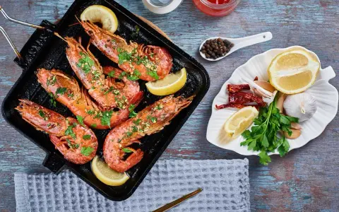 Deliciosos langostinos a la plancha, servidos con rodajas de limón y perejil fresco. Acompañados de ajo, guindillas y granos de pimienta.