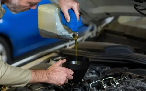 Mecánico vertiendo aceite nuevo en el motor para el mantenimiento del coche.