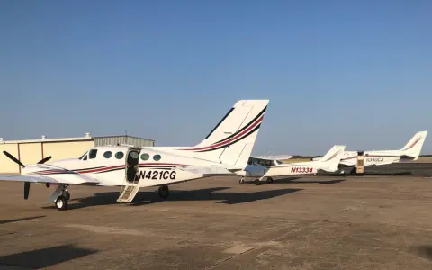 Mehrere weiße Cessna zweimotorig Flugzeuge stehen auf dem Flugplatz. Eines hat die Tür geöffnet.