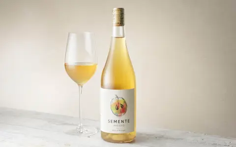 En flaska och ett glas med gyllene Semente Avesso vin.