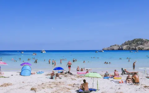 Słoneczna plaża na Majorce, pełna ludzi kąpiących się i opalających. Idealne majorka atrakcje dla dzieci i dorosłych.