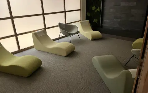 Un espace d'accueil moderne avec des chaises longues confortables et un mur végétal apaisant.