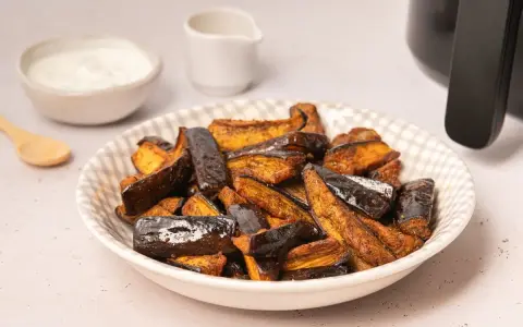Berenjenas en freidora de aire, doradas y crujientes, listas para disfrutar con un dip cremoso.