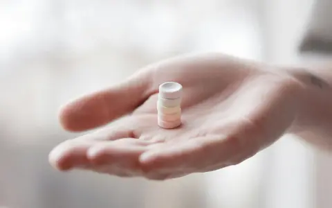 Eine Hand hält einen Stapel bunter Pillen. Vielleicht L-Arginin vor dem Schlafen für einen erholsamen Schlaf.