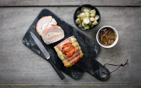 Un délicieux roti de porc Orloff, tranché et garni, accompagné de légumes et d'une sauce onctueuse.