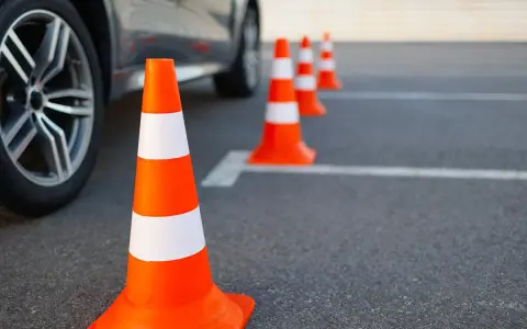 Pomarańczowe pachołki na placu manewrowym. Zastanawiasz się, jakie prawo jazdy potrzebne na autolawetę?