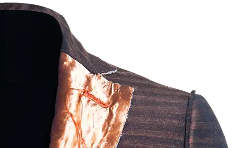 Dettaglio di una giacca destrutturata Armani con fodera color rame e cuciture a vista.