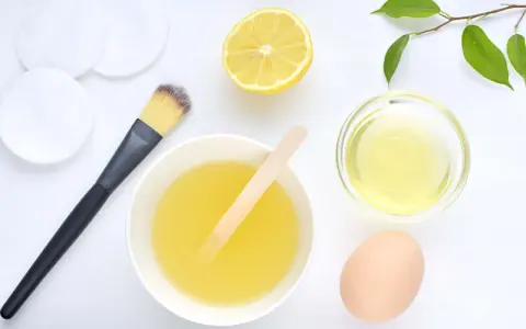 Ingredientes para una mascarilla casera para el pelo: limón, huevo, aceite y aplicador.
