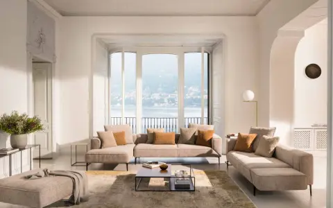 Un salon blanc et beige cocooning, avec des canapés confortables, un tapis doux et une vue imprenable sur un lac.