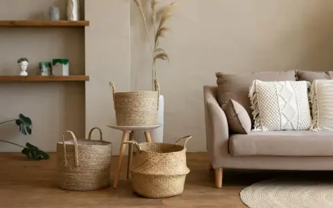 Przytulny salon w stylu boho: plecione kosze, beżowa kanapa z makramową poduszką i suszone trawy.