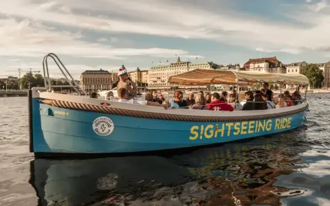 En blå båt med texten "SIGHTSEEING RIDE" tar passagerare på en tur i Stockholm.