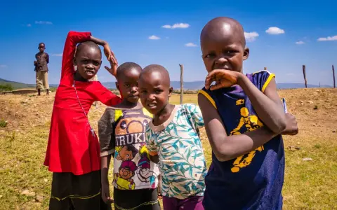 Dzieci z plemienia Masajów, żyjących w Kenii i Tanzanii, pozują do zdjęcia na tle sawanny.