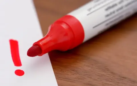 Roter Filzstift schreibt ein Ausrufezeichen auf weißes Papier. Ein wichtiger Hinweis, der sich leicht vom Filzstift von Haut entfernen lässt.